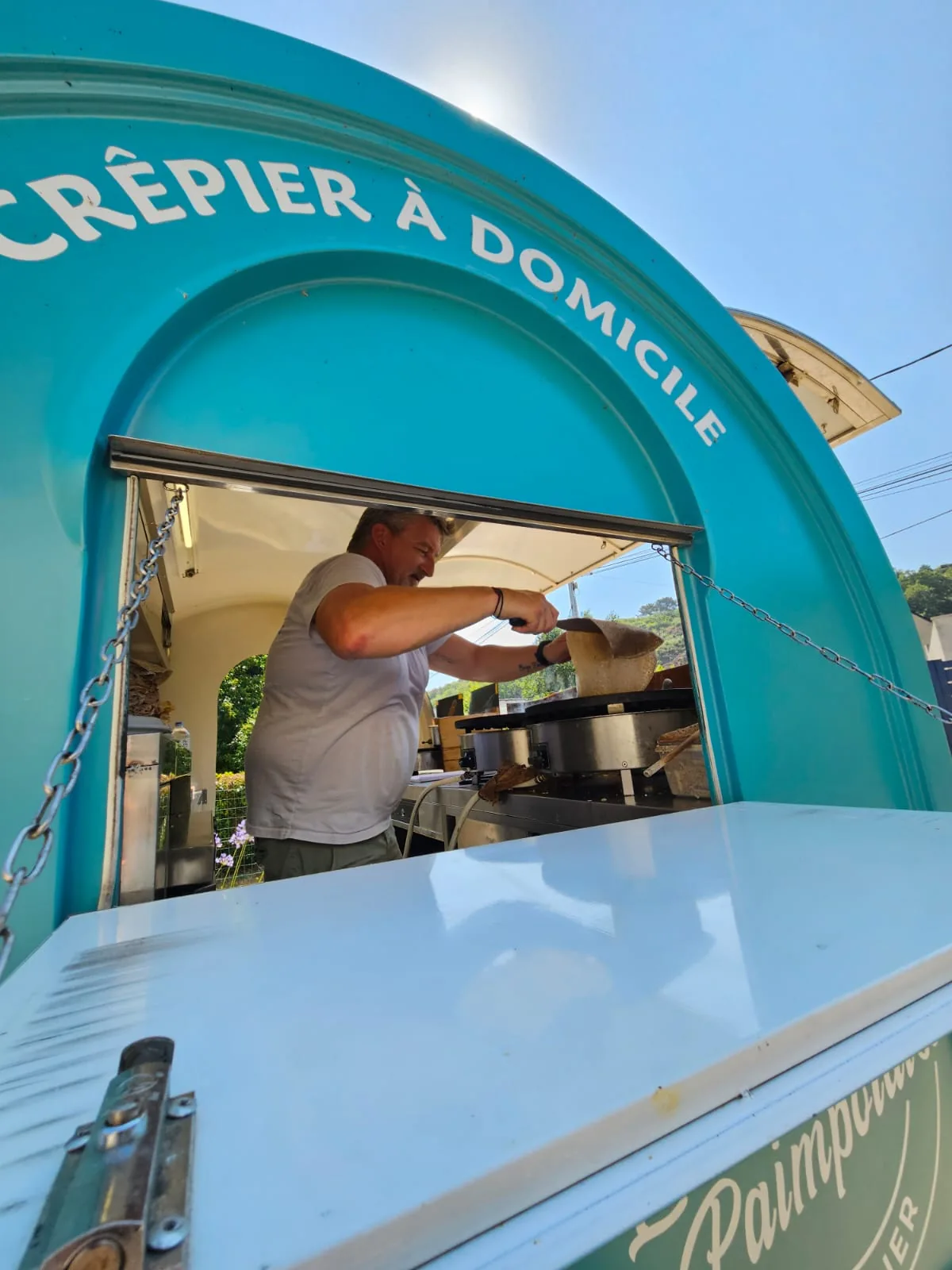 Anthony préparant une crêpe dans sa remorque turquoise