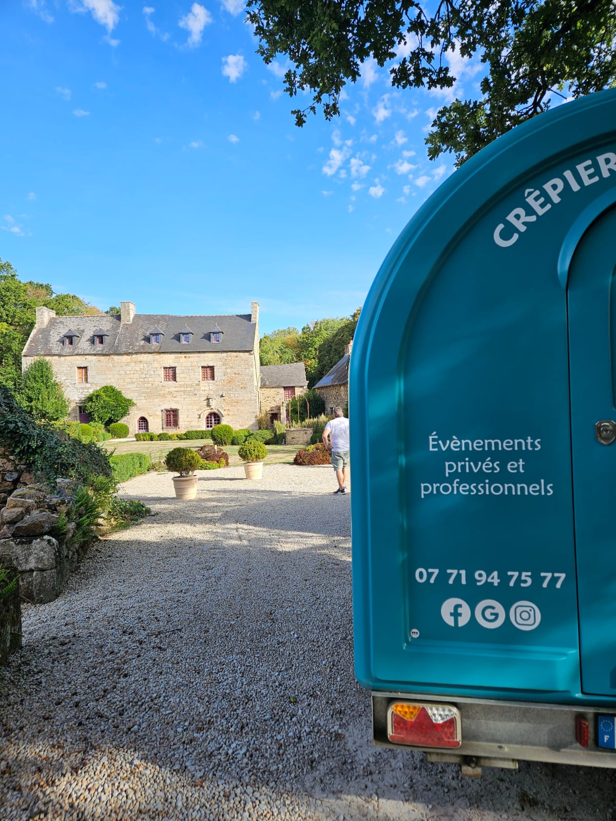Remorque turquoise de La Galette Paimpolaise devant un domaine en pierre, cadre de réception